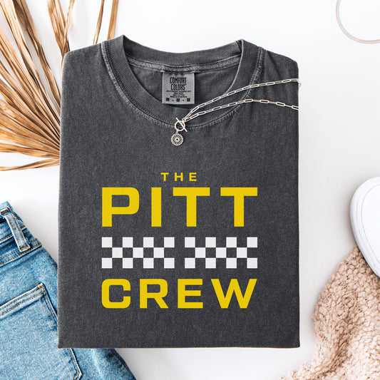 Folded dark gray t-shirt with 'The Pitt Crew' text in yellow on a white background