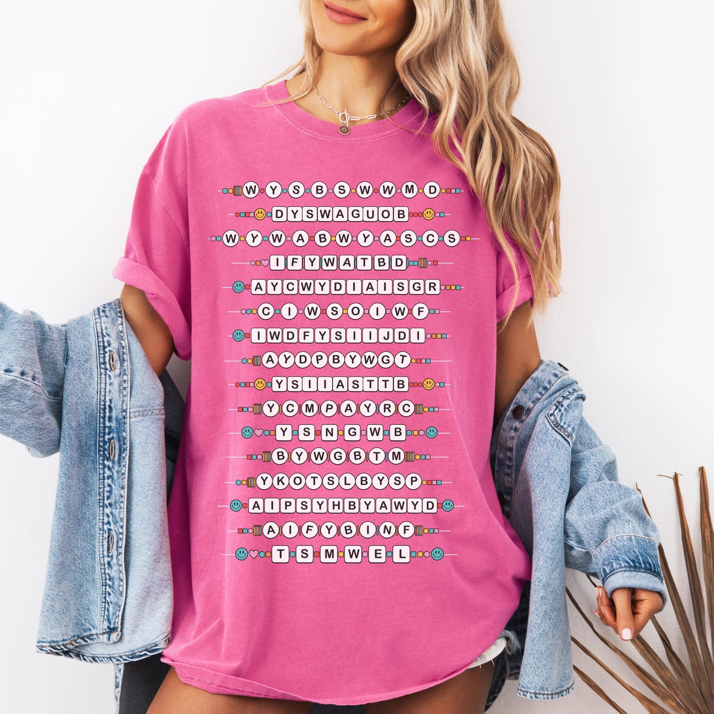 Woman wearing a pink t-shirt with smallest man text design, holding a denim jacket.