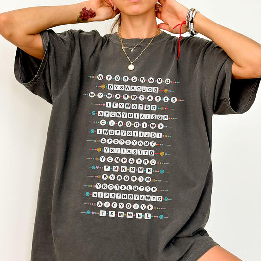 Person wearing a dark gray t-shirt with colorful smallest man text design on a plain background