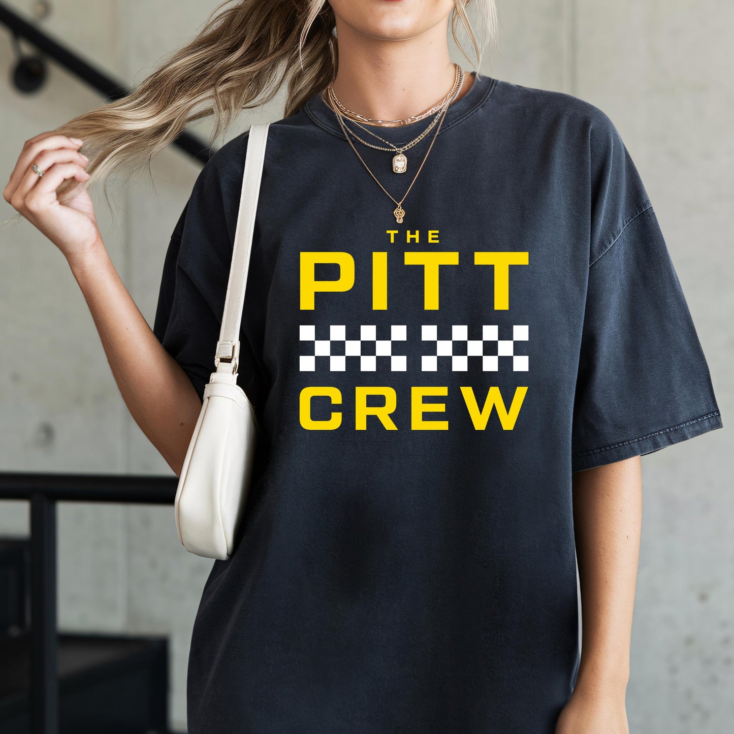Person wearing a black t-shirt with 'The Pitt Crew' text in yellow and white checkered pattern.