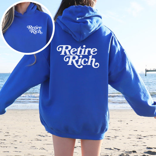 Person wearing a blue hoodie with 'Retire Rich' text on a beach