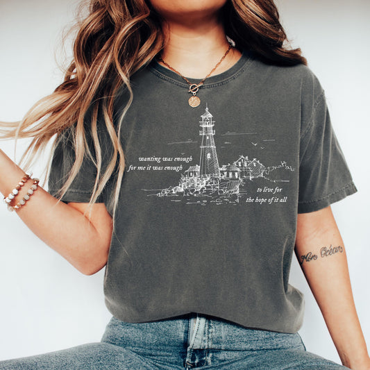 Person wearing a dark gray t-shirt with a lighthouse design and wanting was enough for me it was enough text.