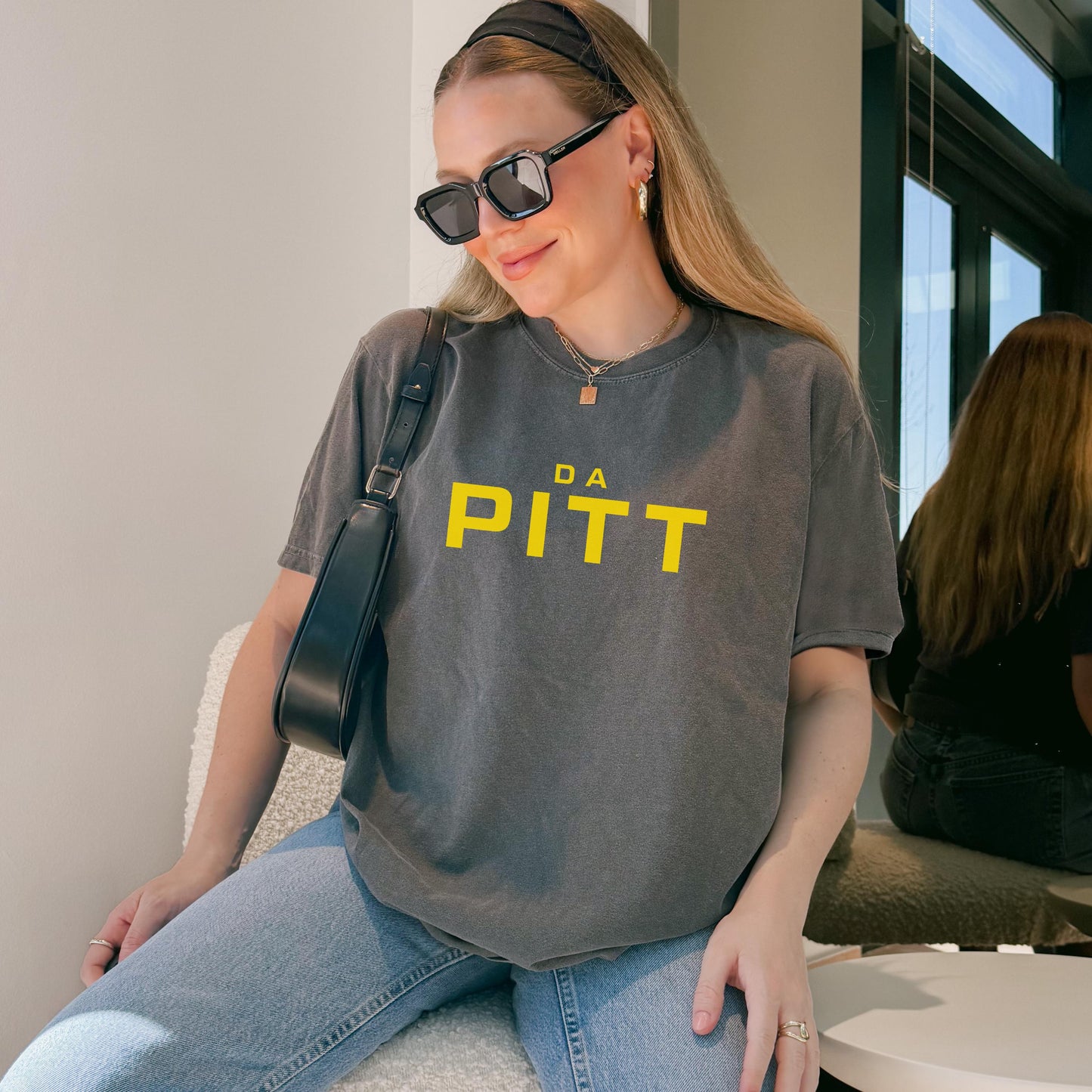 Pepper-washed gray t-shirt with yellow “DA PITT” lettering, worn casually with jeans.