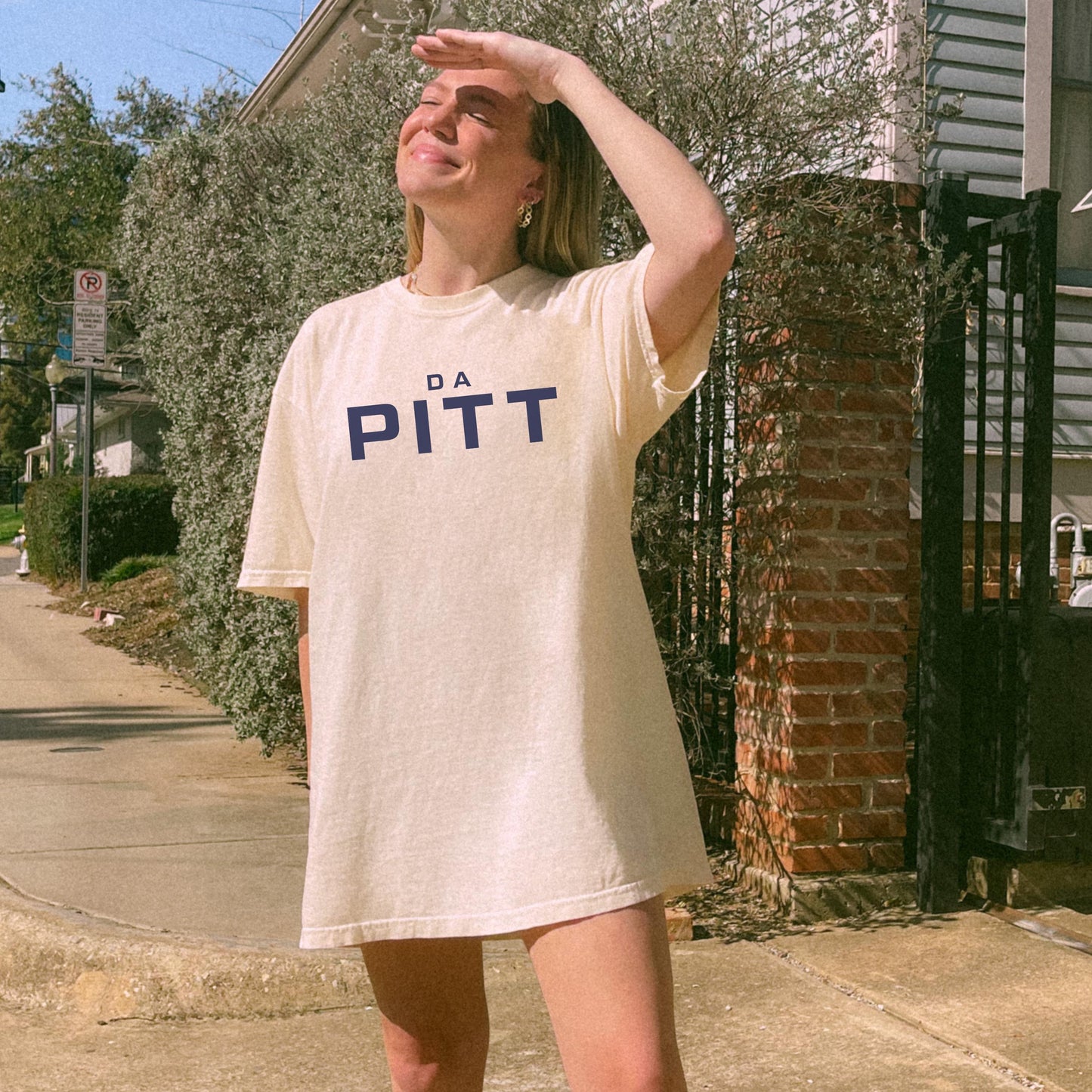 Model wearing ivory tee with navy “DA PITT” lettering, styled oversize