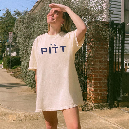 Model wearing ivory tee with navy “DA PITT” lettering, styled oversize